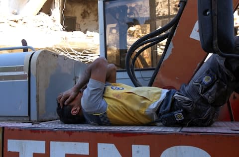 A member of the Syrian civil defence, known as the White Helmets, rests after searching for victims under the rubble of buildings in Maaret al-Numan - Credit: AFP