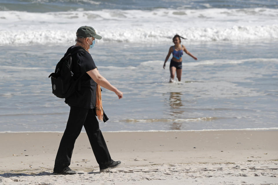 Una mujer camina junto a la orilla en la playa Jones Bach, en Wantagh, Nueva York, el 21 de mayo del 2020. Los neoyorquinos ansiosos por dos meses de cuarentena por coronavirus recibieron un inesperado alivio cuando el gobernador Andrew Cuomo aflojó las restricciones a reuniones públicas en el estado para el feriado del Día de los Caídos en Guerras. (AP Foto/Kathy Willens)