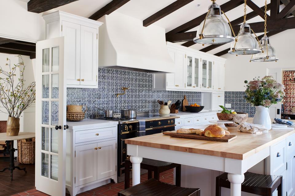 Colorful Mosaic House tiles play off traditional details like the Nanz Company hardware and Ann-Morris pendants and stools in the kitchen, which was gutted and reframed to create more generous proportions and an era-appropriate aesthetic.