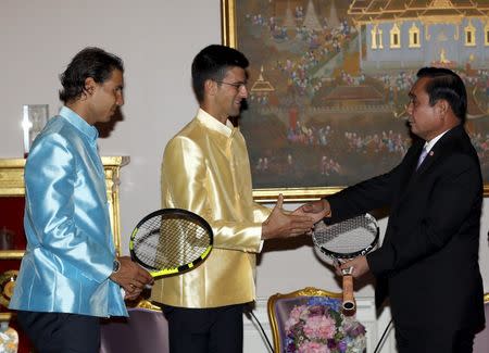 Tennis players Novak Djokovic (C) of Serbia and Rafael Nadal (L) of Spain give rackets to Thai Prime Minister Prayut Chan-o-cha (R) during a meeting at the Government House in Bangkok, Thailand, October 2, 2015. REUTERS/Rungroj Yongrit/Pool