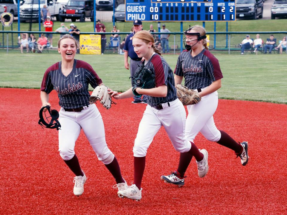 Bella Daniels, middle, is congratulated by shortstop Estelle Matheney, left, and second baseman Sarah Wayne after her inning-ending double play helped secure a 6-0 win against Morgan in a Division II district semifinal on Monday at the Philo Athletic Complex in Duncan Falls.