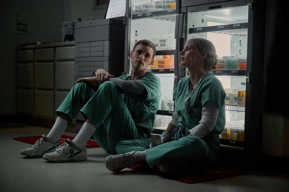Charlie and Amy sit side-by-side on the floor, leaning up against a fridge full of medical samples