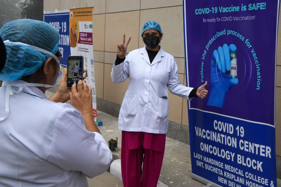 A healthcare worker poses for a photo beside a poster about the Covid-19 coronavirus vaccine at the Kalawati hospital in New Delhi on January 16, 2021. (Photo by Prakash SINGH / AFP) (Photo by PRAKASH SINGH/AFP via Getty Images)