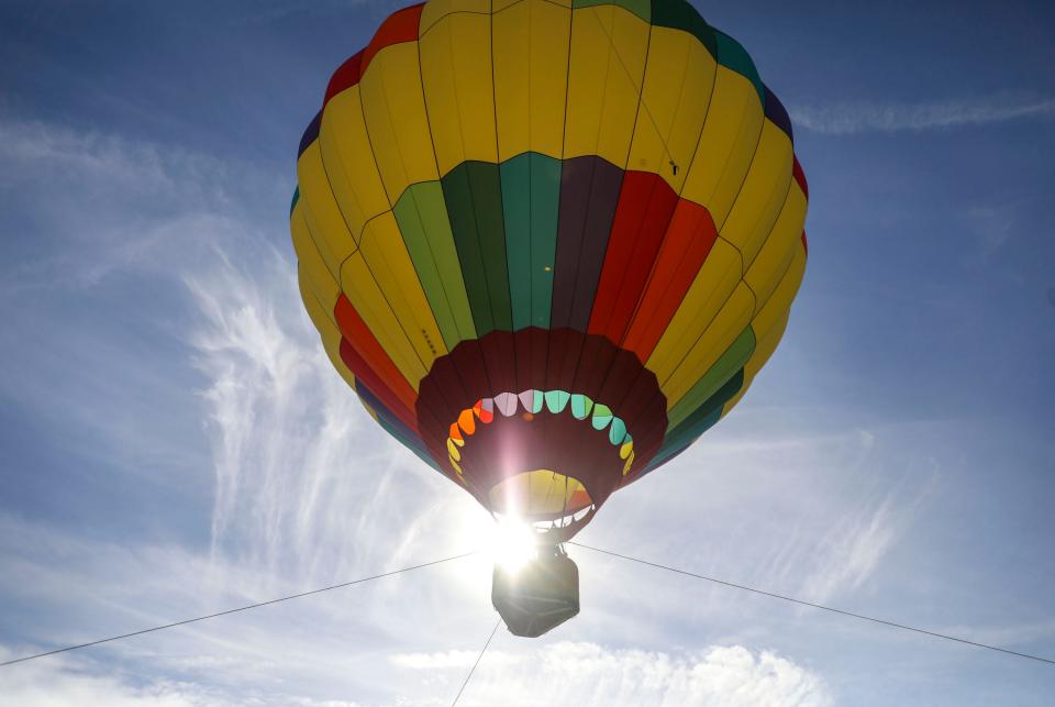 A tethered hot air balloon takes passengers up for a ride, Saturday, Nov. 20, 2021, in Cathedral City, Calif. 