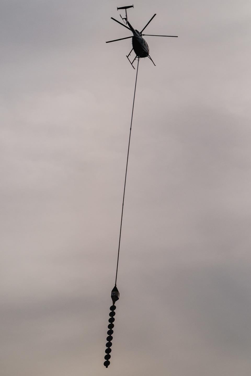 A helicopter aerial saw is seen in operation along Ohio 212 near New Cumberland on Wednesday.