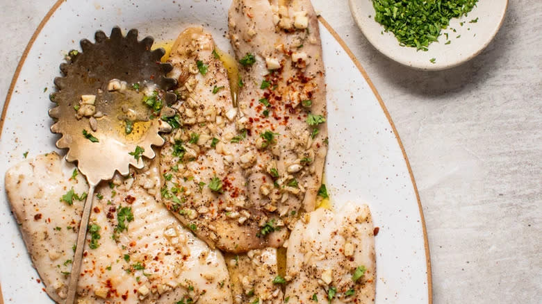 Fish fillets with herbs and serving spoon