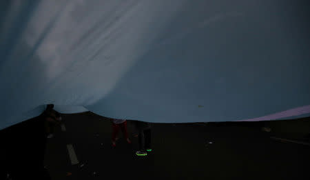 A child wears shoes with lights on its soles as he playes beneath a large Argentine national flag during a protest against a cost increase in public and utility services in Buenos Aires, Argentina, January 10, 2019. REUTERS/Marcos Brindicci