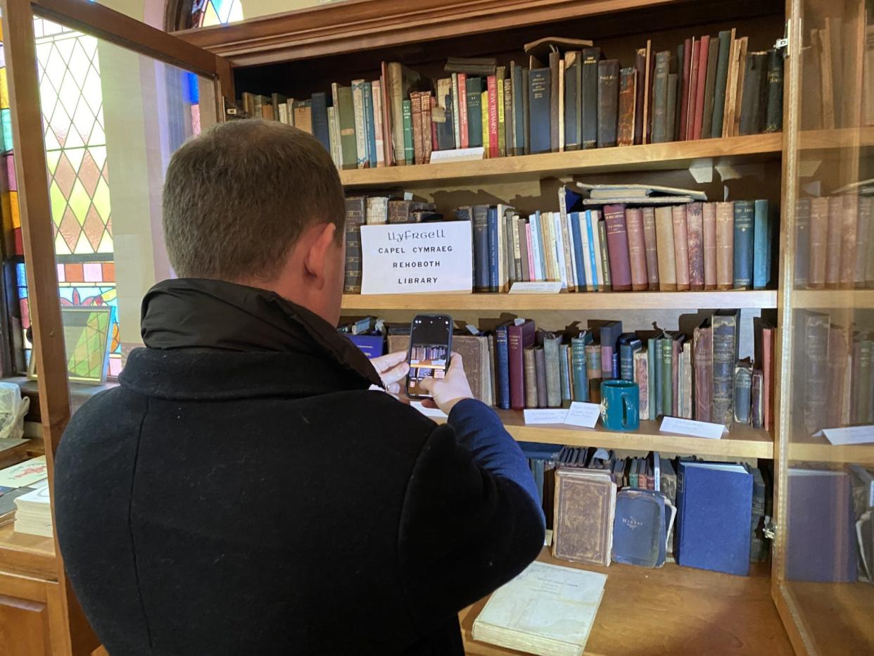 Rhys ab Owen, a member of the Welsh Parliament, captures the Welsh-language library at Rehoboth Welsh Chapel in Delta. The Rev. Richard Baskwell, pastor of the church, says the library is the largest of its type that he’s seen in America.