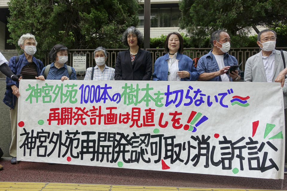 Some of the plaintiffs suing the Tokyo Metropolitan Government to stop its approval of a controversial redevelopment plan for a historic and beloved park area stand outside of the Tokyo District Court in Tokyo Thursday, June 29, 2023, before their first hearing in the case. A banner reads, “Please do not cut 1,000 trees at Jingu Gaien.” Critics of the planned redevelopment of a beloved centuries-old Tokyo park and historic sports stadiums accused the government in court on Thursday of ignoring the wishes of residents and catering to commercial interests. (AP Photo/Mari Yamaguchi)