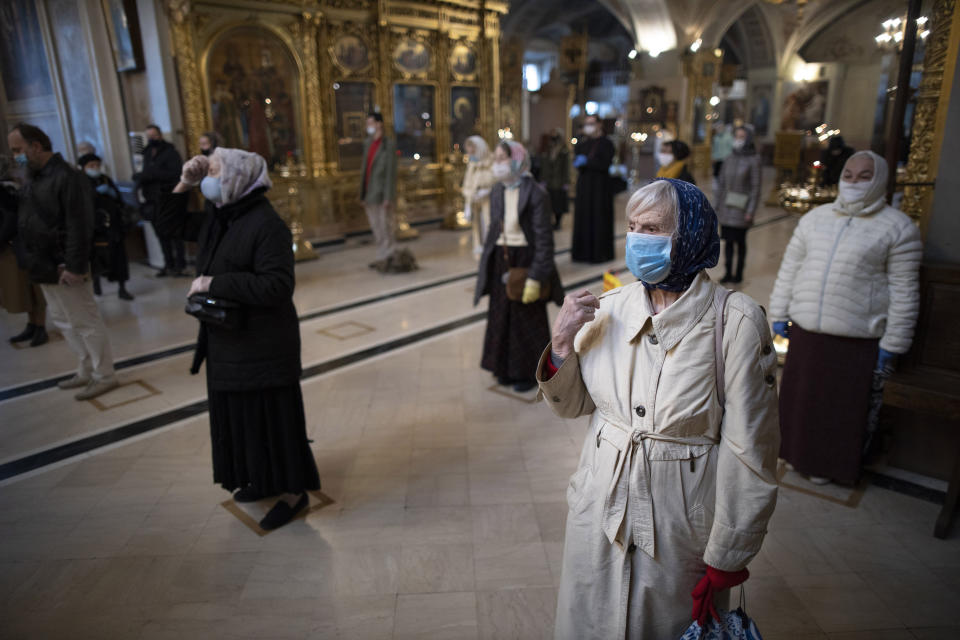 Parishioners wearing face masks to protect against coronavirus, observe social distancing guidelines cross themselves as they attend service at the Epiphany Cathedral in Moscow, Russia, Tuesday, June 2, 2020. Churches in Moscow reopen to believers after a two-month lockdown imposed to control the spread of the coronavirus. (AP Photo/Alexander Zemlianichenko)