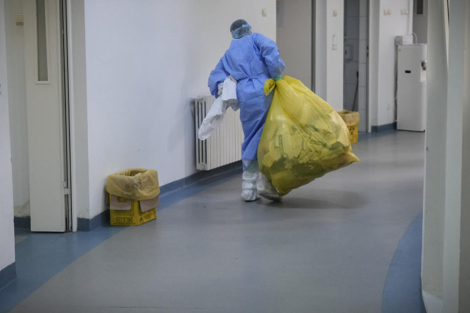 A woman carries a sack of medical waste at the COVID-19 unit of the Marius Nasta National Pneumology Institute in Bucharest, Romania, Thursday, Sept. 23, 2021. Daily new coronavirus infections in Romania, a country of 19 million, have grown exponentially over the last month, while vaccine uptake has declined to worrying lows. Government data shows that 91.5% of COVID-19 deaths in Romania between Sept. 18-23 were people who had not been vaccinated. (AP Photo/Vadim Ghirda)