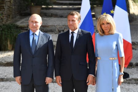 French President Emmanuel Macron and his wife Brigitte Macron pose with Russia's President Vladimir Putin, at the French President's summer retreat of the Bregancon fortress on the Mediterranean coast, near the village of Bormes-les-Mimosas