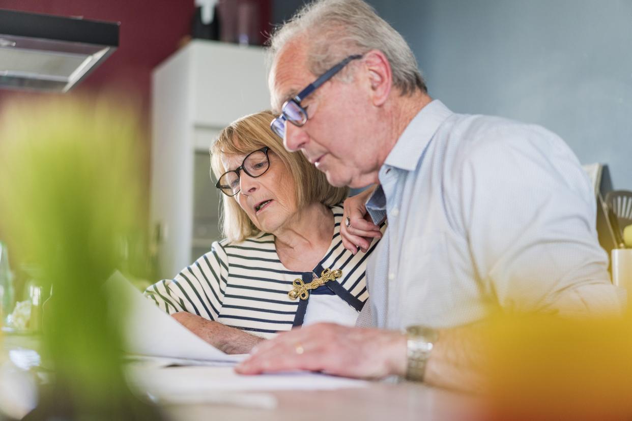 senior couple looking at documents. Man and woman are examining bills at table