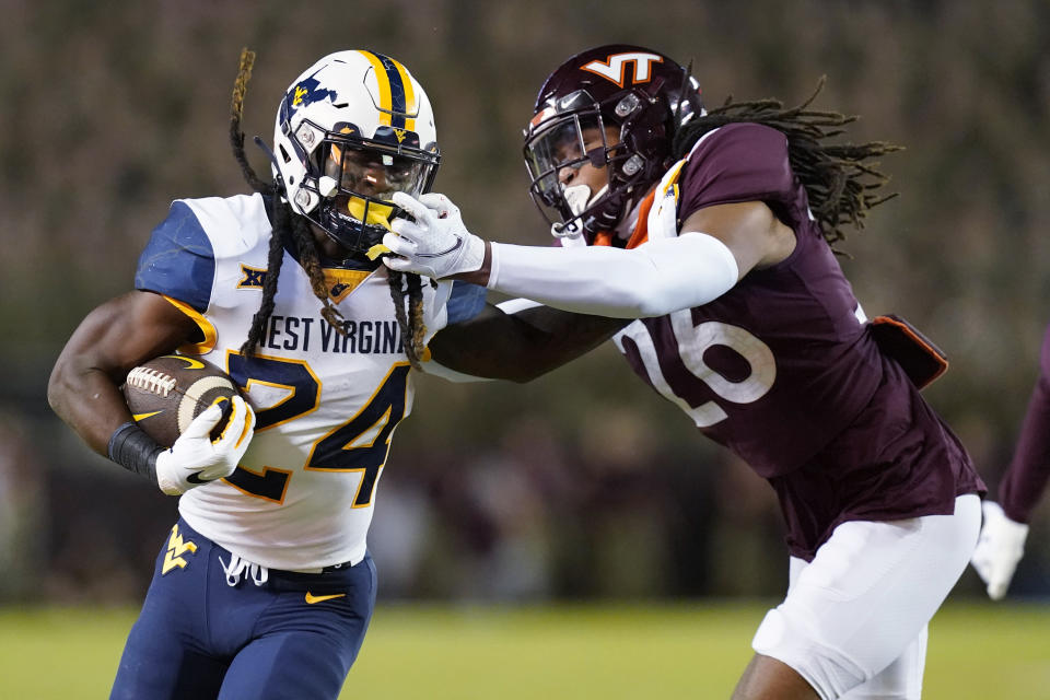 Virginia Tech defensive back Jalen Stroman (26) grabs the face mask of West Virginia running back Tony Mathis Jr. (24) during the first half of an NCAA college football game Thursday, Sept. 22, 2022, in Blacksburg, Va. (AP Photo/Steve Helber)