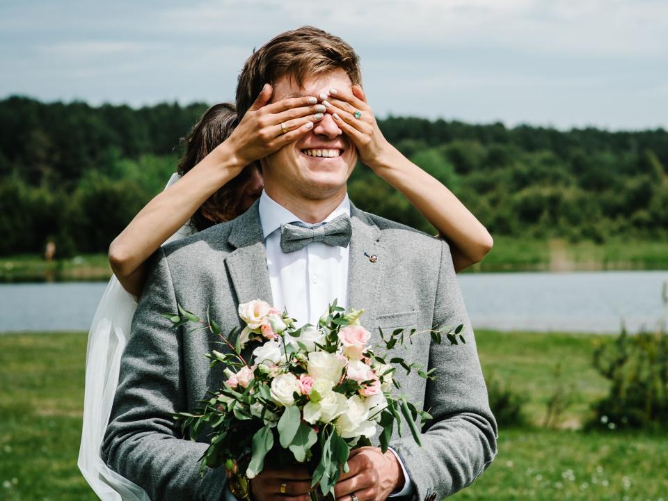 The first meeting is newlyweds on a green field outdoors. Bride goes back to the groom, surprise in nature. The woman closed her eyes to her husband.