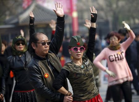 A woman dressed in military style clothes performs square dancing with a man at a park square in Beijing, China, April 9, 2015. REUTERS/Kim Kyung-Hoon