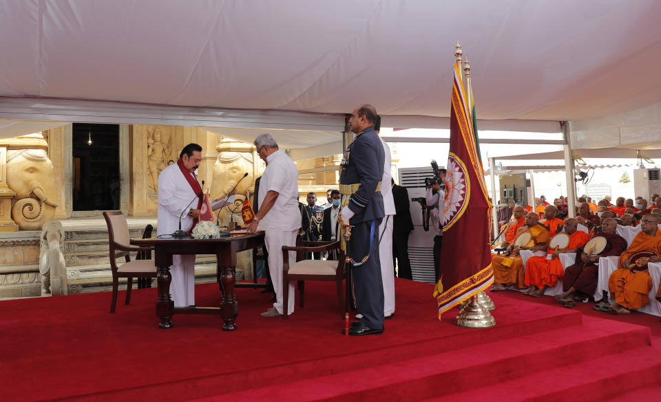 Sri Lanka’s former President Mahinda Rajapaksa, left, takes oath as the prime minister before his younger brother, President Gotabaya Rajapaksa, at Kelaniya Royal Buddhist temple in Colombo, Sri Lanka, Sunday, Aug. 9, 2020. (AP Photo/Eranga Jayawardena)