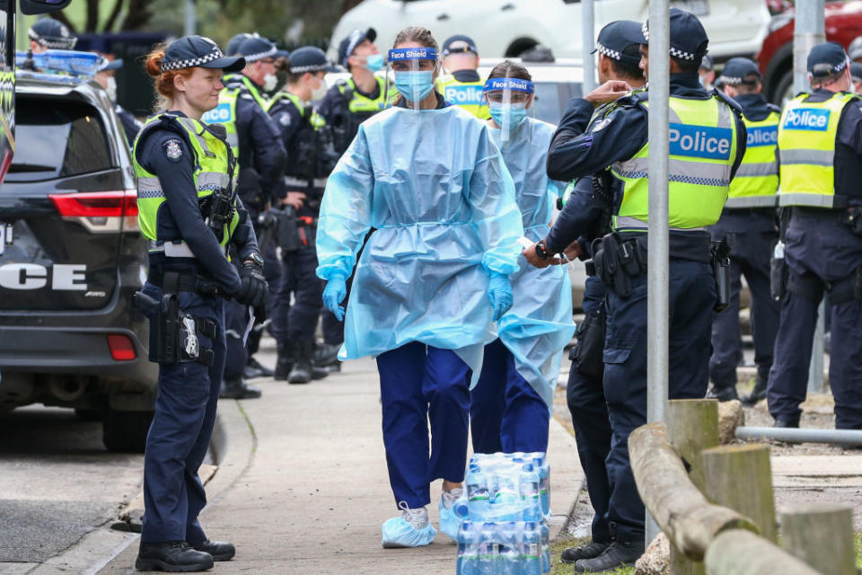 Medical staff wearing PPE holding material about to walk into the Flemington Public housing flats on July 5.