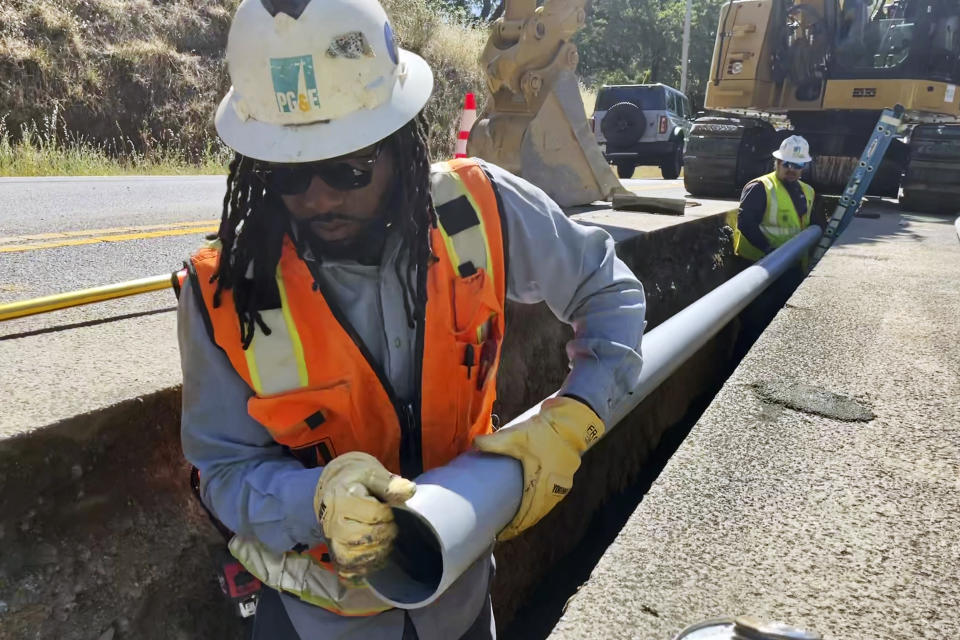Aaron Morgan, with a PG&E crew, works at installing underground power lines along Porter Creek Road in Sonoma County, Calif., site of the 2017 Tubbs Fire, on Monday, June 13, 2022. Pacific Gas & Electric Co. has started an ambitious project to bury underground thousands of miles of power lines in an effort to prevent igniting fires with its equipment and avoid shutting down power during hot and windy weather. (AP Photo/Haven Daley)
