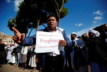 A Muslim holds a placard reading "To close a place of prayer is an act against the faith" as he attends Friday prayers in front of the Colosseum in Rome, Italy October 21, 2016, to protest against the closure of unlicensed mosques. REUTERS/Tony Gentile