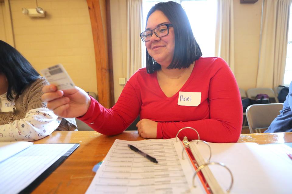 Poll worker Ariel Dashner checks a voter's ID at the Hart Park Muellner Building in Wauwatosa.