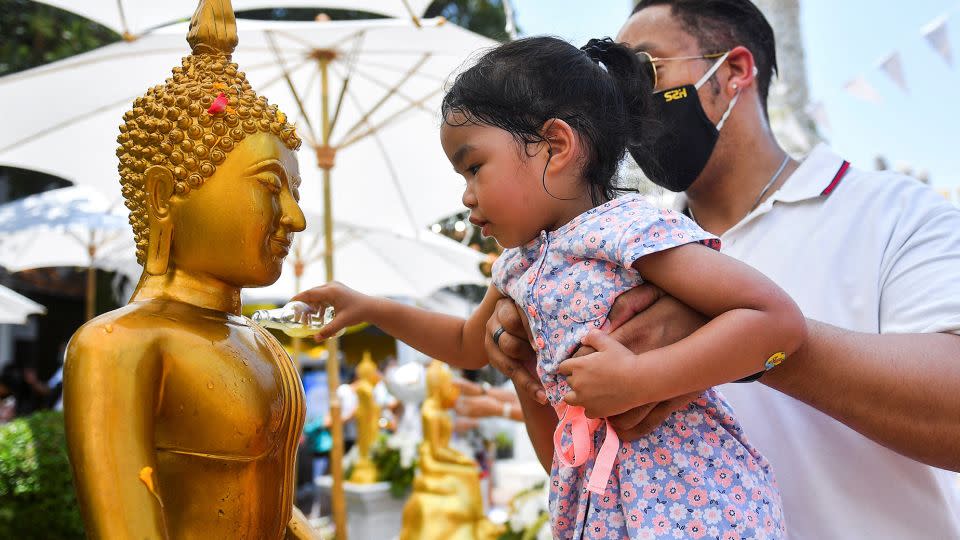 A girl pours water on a Buddha statue during the Songkran holiday, a ritual known as Song Nam Phra. - Chalinee Thirasupa/Reuters