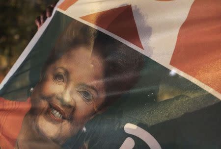 A supporter holds a flag with an image of Brazil's President and Workers' Party (PT) presidential candidate Dilma Rousseff on the street, before a television debate of Brazil's presidential candidates, in Sao Paulo September 28, 2014. REUTERS/Nacho Doce