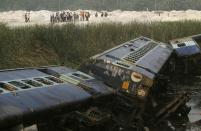 Locals and others look at a train that derailed near Jagiroad Railway Station, about 90 kilometers (56 miles) east of Gauhati, India, Wednesday, April 16, 2014. According to a Northeast Frontier Railway officer, dozens of people were injured when the train jumped the tracks and derailed early Wednesday. (AP Photo/Anupam Nath)