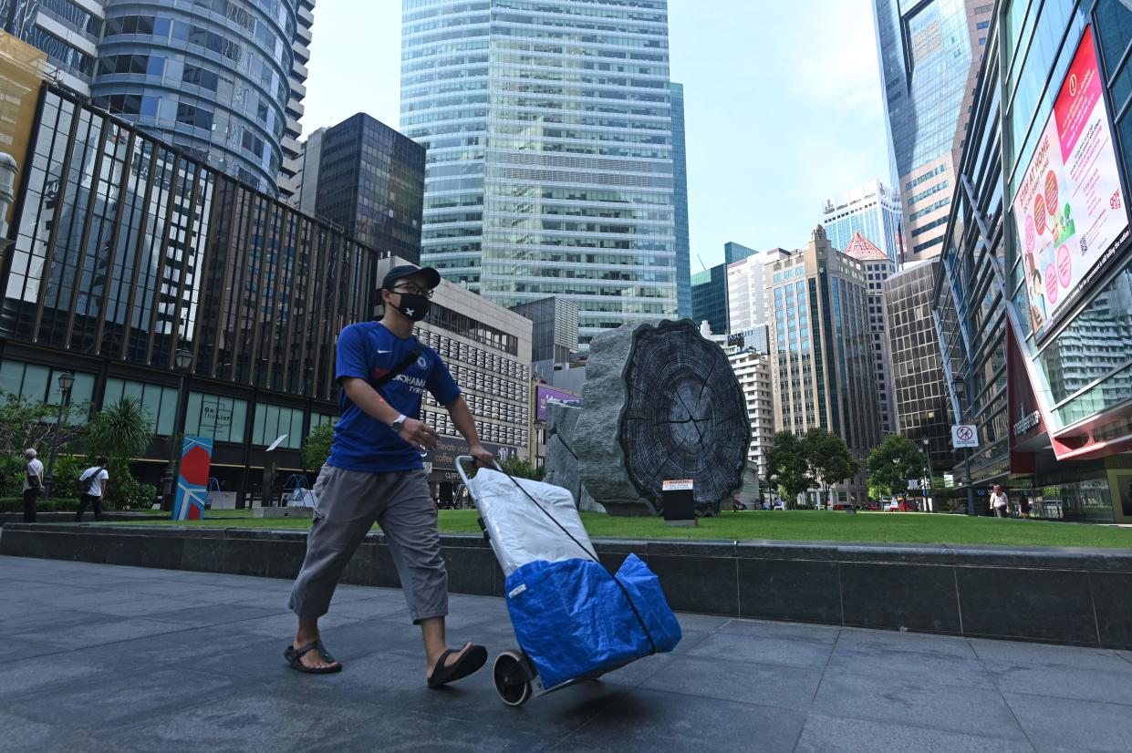 A man wearing a mask as a preventive measure against the spread of the COVID-19 coronavirus pushes a trolley in the Raffles Place financial business district in Singapore on April 14, 2020. (Photo by ROSLAN RAHMAN / AFP) (Photo by ROSLAN RAHMAN/AFP via Getty Images)