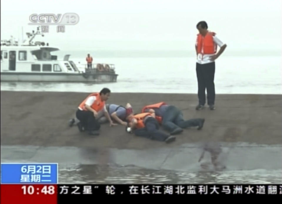 In this image taken from video released by China's CCTV, rescue workers listen for a response to their tapping on the hull of a capsized ship on the Yangtze River in central China's Hubei province Tuesday, June 2, 2015. The small cruise ship sank overnight in China's Yangtze River during a storm, state media said Tuesday. Chinese words on the bottom read "Ferry capsize on Yangtze." (CCTV via AP Video)