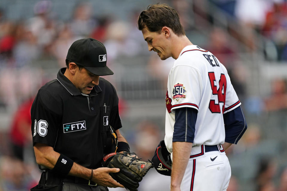 Umpire David Rackley (86) inspects Atlanta Braves starting pitcher Max Fried's glove before a baseball game against the Tampa Bay Rays, Saturday, July 17, 2021, in Atlanta. (AP Photo/John Bazemore)