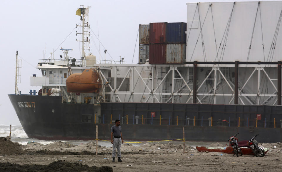 A Pakistan Navy officer stands near the stranded Heng Tong 77 cargo ship at Sea View Beach near the southern port city of Karachi, Pakistan, Monday, July 26, 2021. Pakistani authorities said they are working on plans to refloat the cargo ship that ran aground last week amid bad weather en route to Istanbul from China. (AP Photo/Fareed Khan)