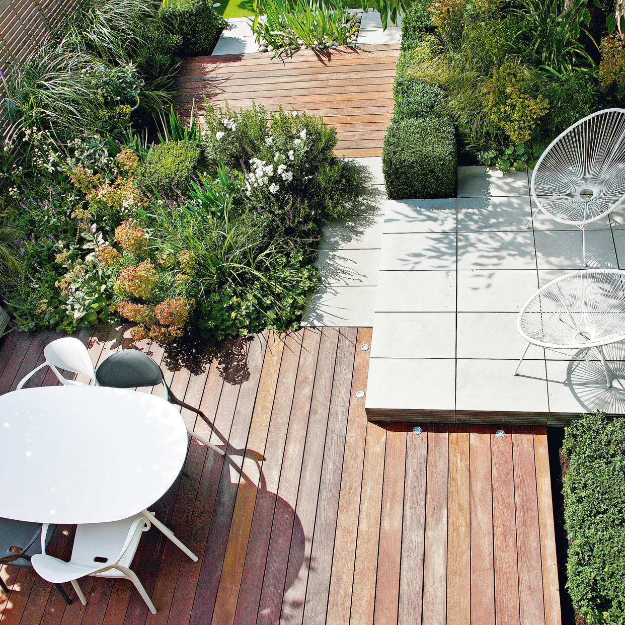  Small paved garden split into zones with blue back wall. 