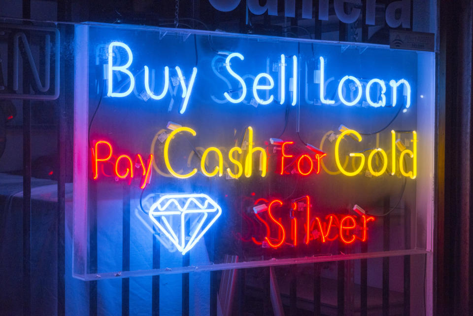 a pawn shop neon sign that says, "buy sell loan pay cash for gold silver"