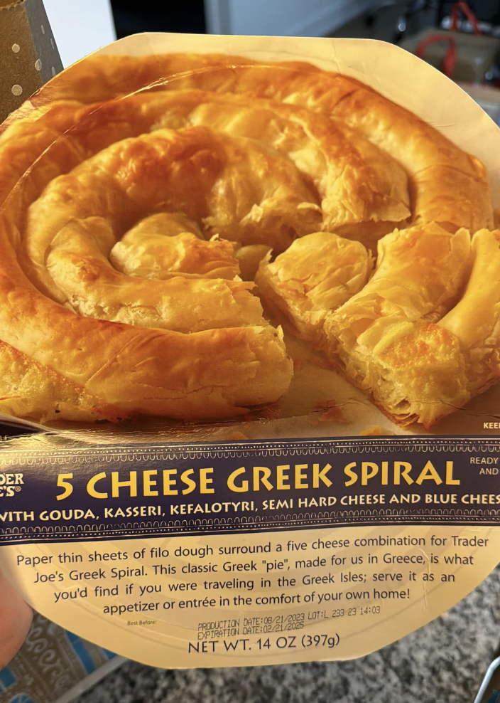 Hand holding a package of Trader Joe's Spiral Cheese Pie with baking instructions visible
