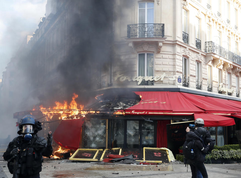 Paris famed restaurant Fouquet's burns on the Champs Elysees avenue during a yellow vests demonstration Saturday, March 16, 2019 in Paris. Paris police say more than 100 people have been arrested amid rioting in the French capital by yellow vest protesters and clashes with police. They set life-threatening fires, smashed up luxury stores and clashed with police firing tear gas and water cannon (AP Photo/Christophe Ena)