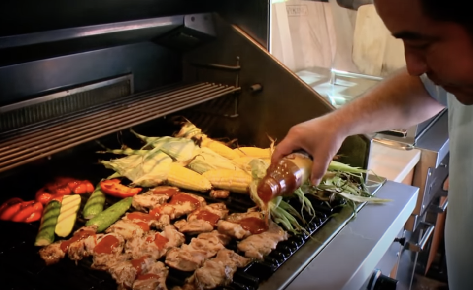 sauce being added meat on the grill