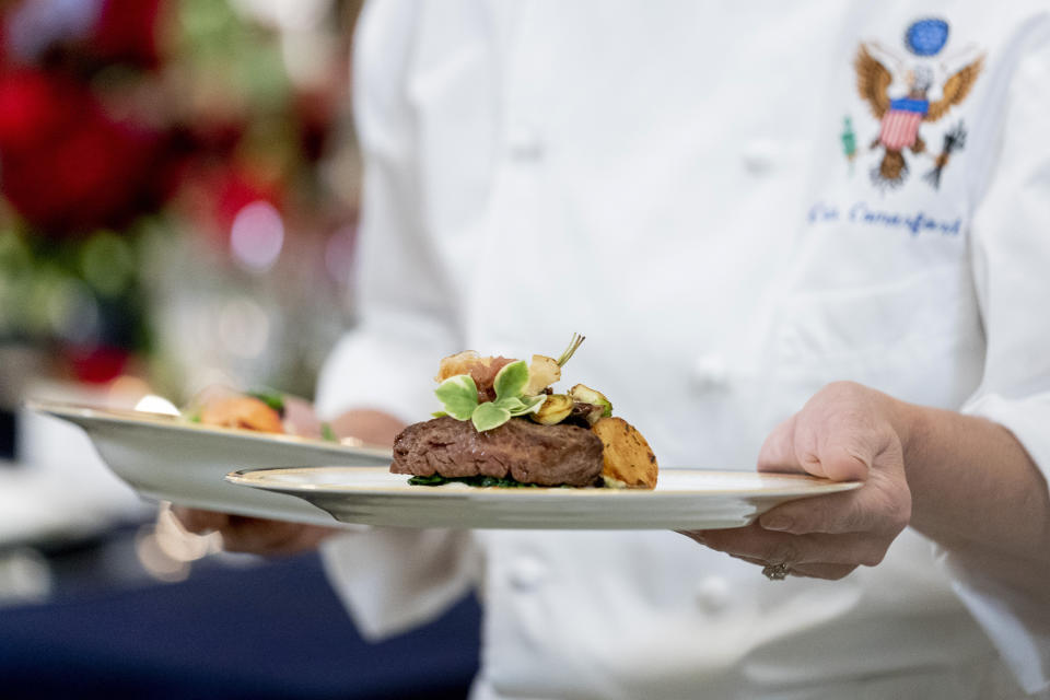 White House executive chef Cris Comerford, holds dishes as she speaks during a media preview for the State Dinner with President Joe Biden and French President Emmanuel Macron in the State Dining Room of the White House in Washington, Wednesday, Nov. 30, 2022. The dinner will include a butter poached maine lobster, a calotte of Beef with shallot Marmalade, American artisanal cheeses, and an orange chiffon cake for desert. (AP Photo/Andrew Harnik)