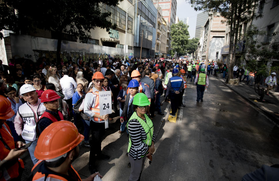 People gather in the street after evacuating their office buildings during an earthquake drill, commemorating the 34th anniversary of the 1985 earthquake, in Mexico City, Thursday, Sept. 19, 2019. The 8.1-magnitude earthquake killed as many as 10,000 and left thousands homeless. The date also commemorates the 2017 earthquake that rattled the city killing hundreds. (AP Photo/Eduardo Verdugo)