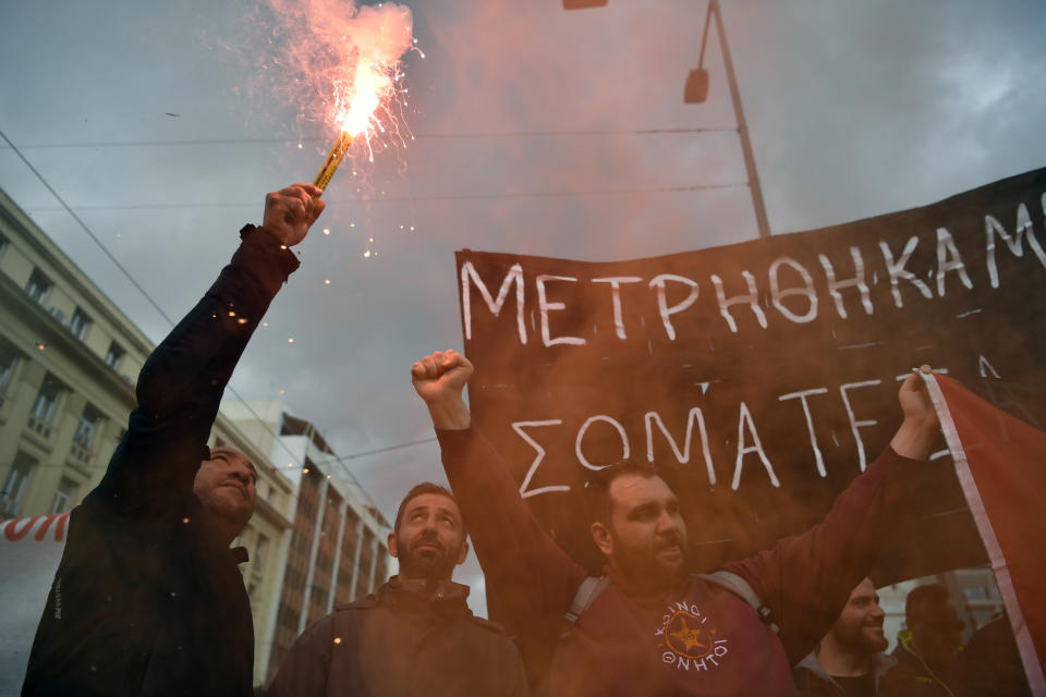 A protester holds a smoke flare during a rally in Athens, Greece, Wednesday, Feb. 28, 2024. Widespread strikes in Greece disrupted transport services Wednesday, halting ferries and trains, in protests timed to coincide with the anniversary of a deadly rail crash a year ago. (AP Photo/Michael Varaklas)