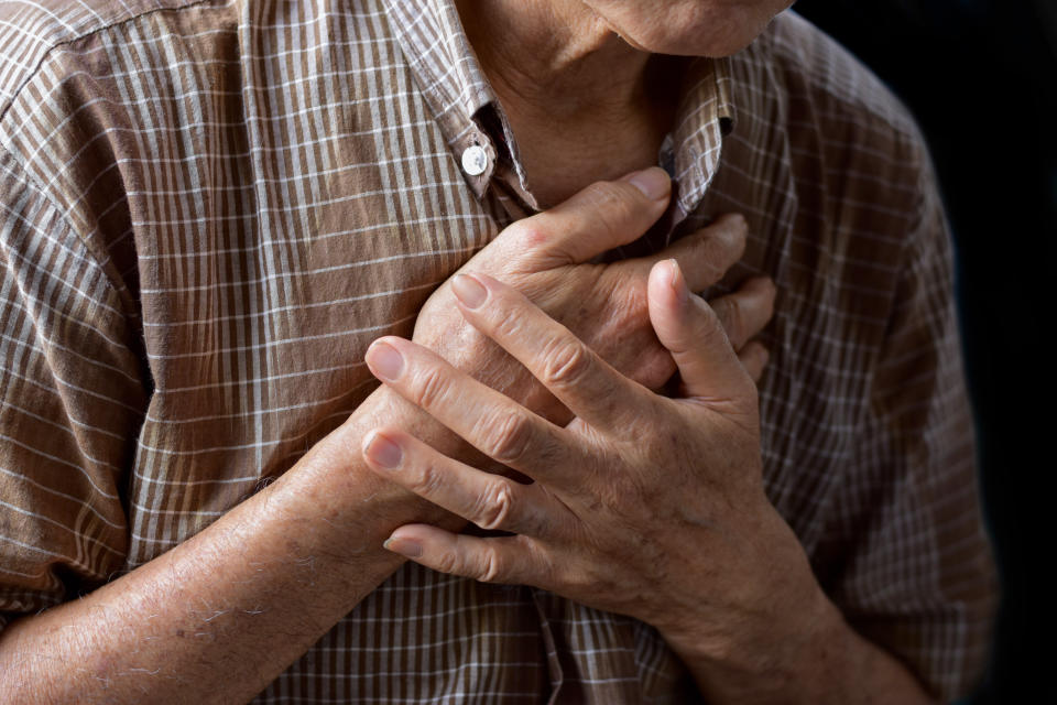 Asian elder man suffering from central chest pain. Chest pain can be caused by heart attack, myocardial infarct or ischemia, myocarditis, pneumonia, oesophagitis, stress, etc,.