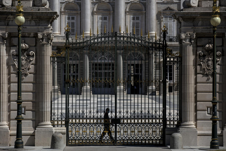 A security guard walks at the Royal Palace in Madrid, Spain, Tuesday, Aug. 4, 2020. Speculation over the whereabouts of former monarch Juan Carlos is gripping Spain, a day after he announced he was leaving the country for an unspecified destination amid a growing financial scandal. (AP Photo/Manu Fernandez)