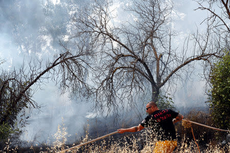 A firefighter puts out a fire near Kibbutz Harel, which was damaged by wildfires during a record heatwave, in Israel May 24, 2019. REUTERS/Ronen Zvulun