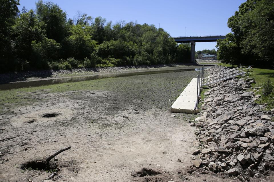 A floating dock lies on the mud in the Appleton navigational canal upstream of Appleton lock 2. The Oneida Street bridge is in the background.