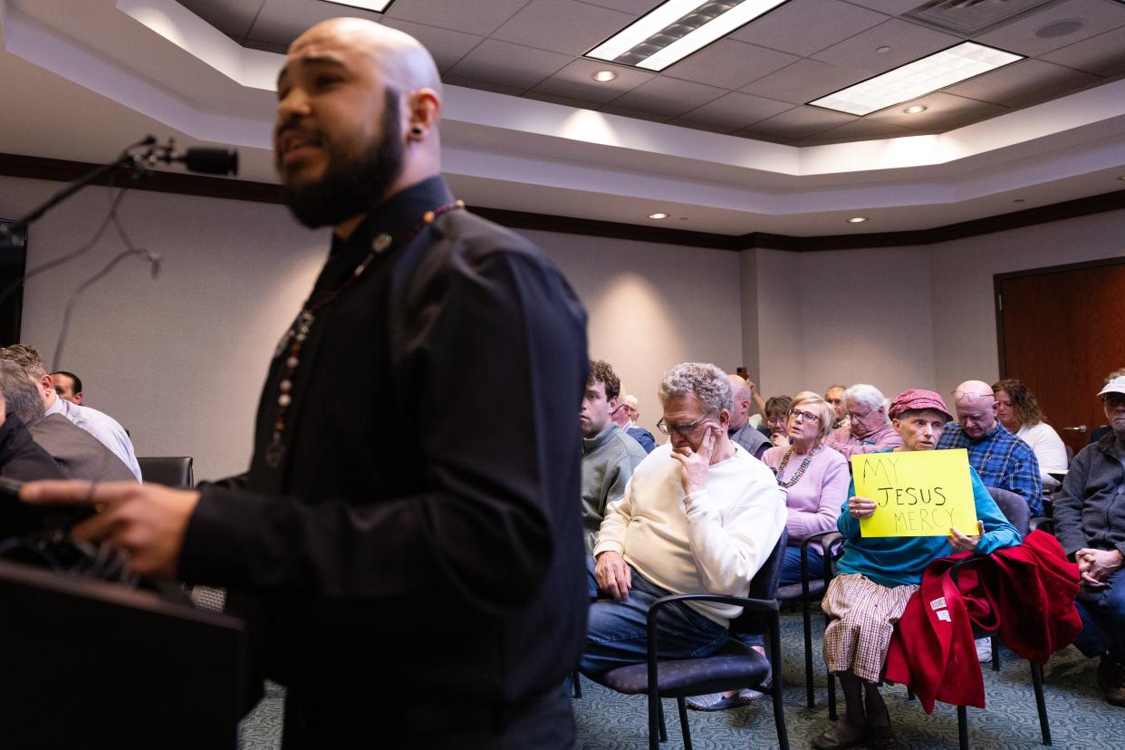 Joan Saintz, of Fennville, holds a sign in protest as Luis Cypher, a minister with The Satanic Temple of West Michigan, gives the invocation on Tuesday, April 23, 2024.