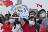 In this photo released by Xinhua News Agency, a woman holds up a card with the words "Dear Motherland, Hello!" as she attends the flag raising ceremony to mark the 73rd anniversary of the founding of the People's Republic of China held at the Tiananmen Square in Beijing on Saturday, Oct. 1, 2022. (Ju Huanzong/Xinhua via AP)