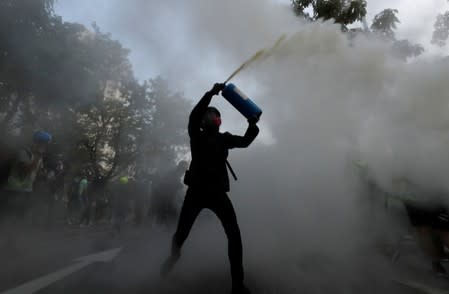 An anti-government protester uses a fire extinguisher during a march in Tuen Mun, Hong Kong