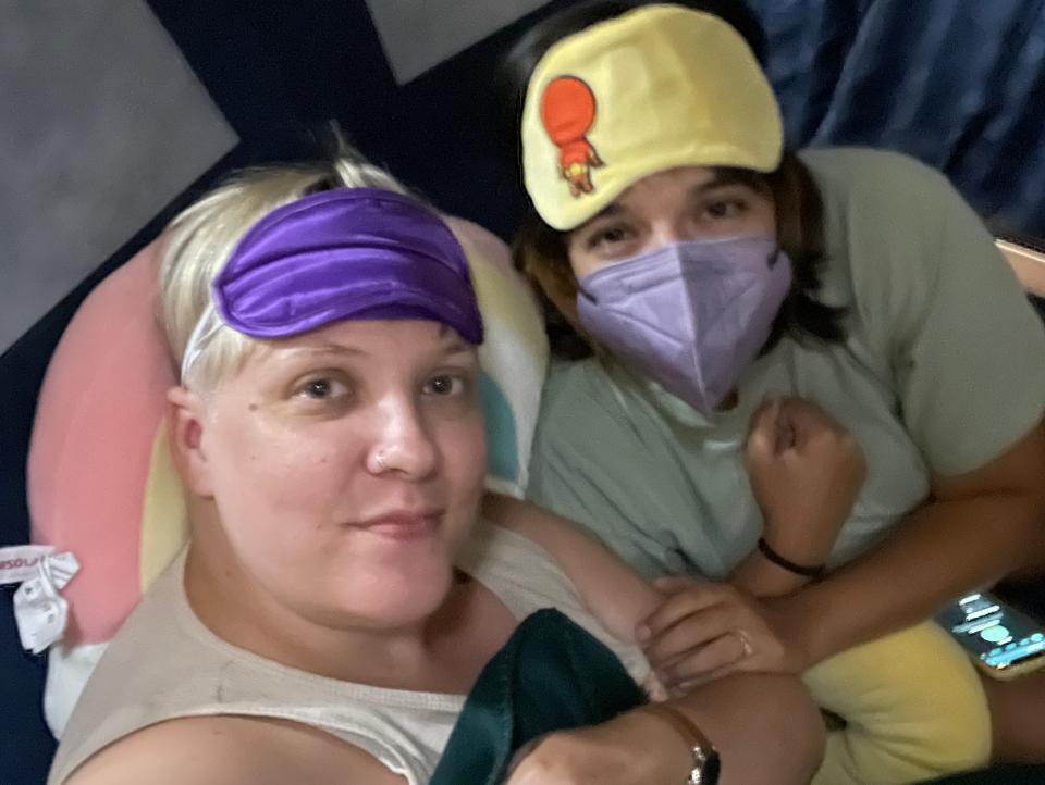 The writer and her wife with masks, sleep masks, and blankets