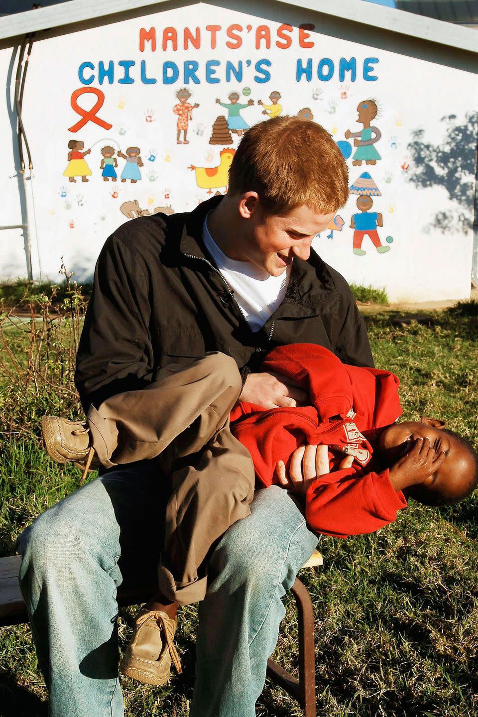 <p>The Duke of Sussex jokes around with a young child during a charitable visit to Lesotho in 2006.</p>