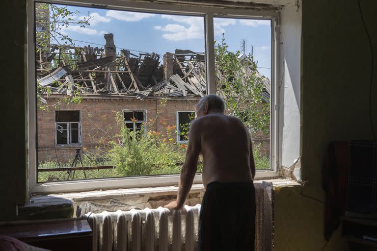 Victor Rosenberg, de 81 años, mira por la ventana de su vivienda destruida por un cohete ruso en el centro de Bajmut, 1º de julio de 2022